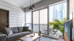 Een moderne woonkamer met een grijze bank, een salontafel en een groot raam met uitzicht op een stadsbeeld.