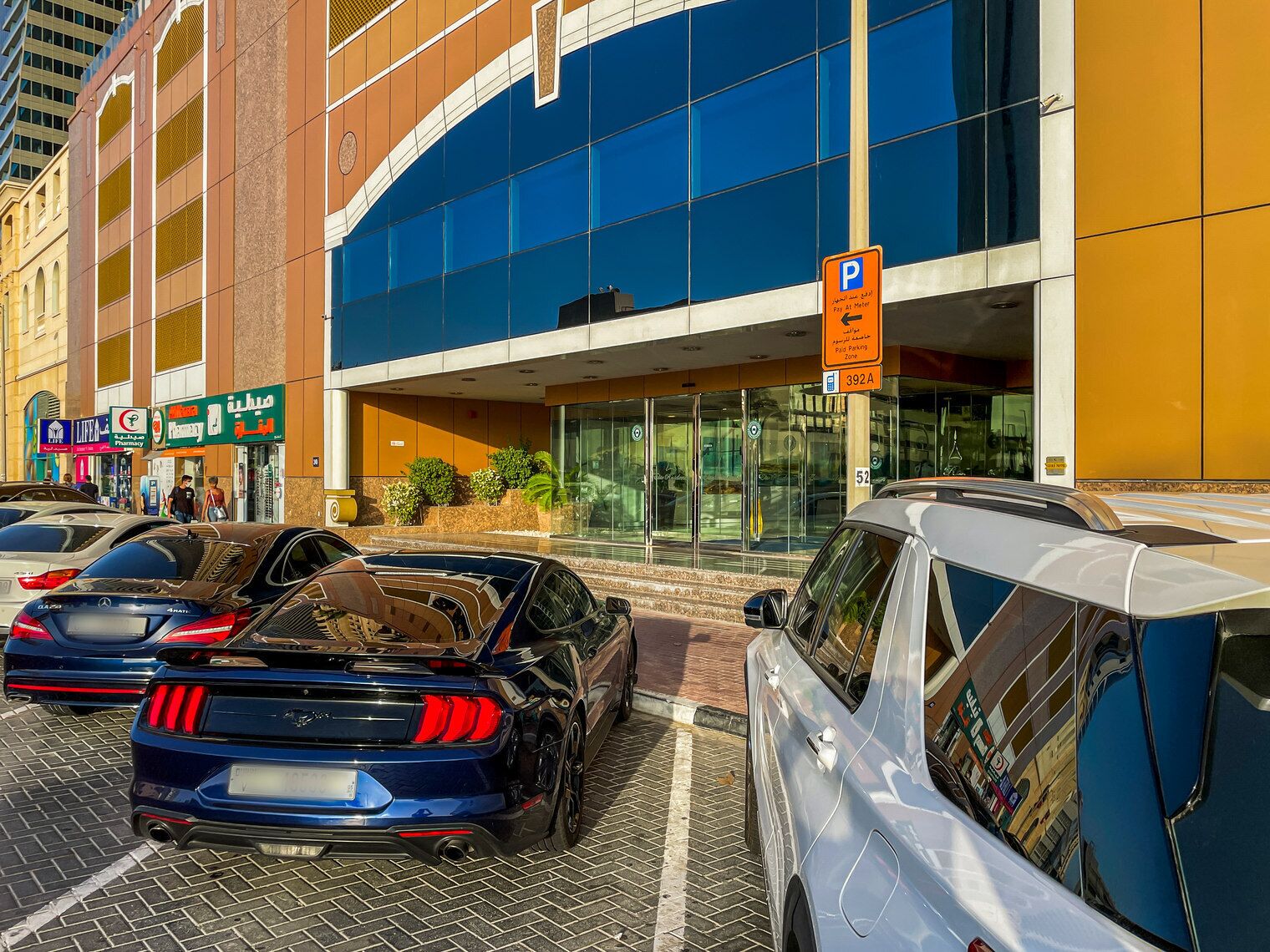 Ein Parkplatz vor einem Gebäude mit blauer Fassade und einem Schild, das eine Parkplatzzone mit Anzeigeverpflichtung kennzeichnet.