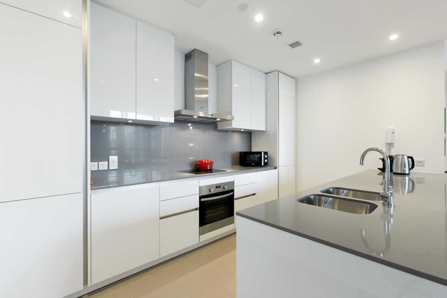 Una cocina moderna con armarios blancos, electrodomésticos de acero inoxidable y una isla grande con un fregadero.