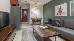 A modern living room with a grey sofa, a wooden coffee table, a TV, and a dining area with a table and chairs. - Blueground | JLT, pool, nr Dubai Marina (Dubai)