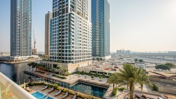 A high-rise building with a swimming pool and lounge area. - Blueground | JLT, pool, nr Dubai Marina (Dubai)