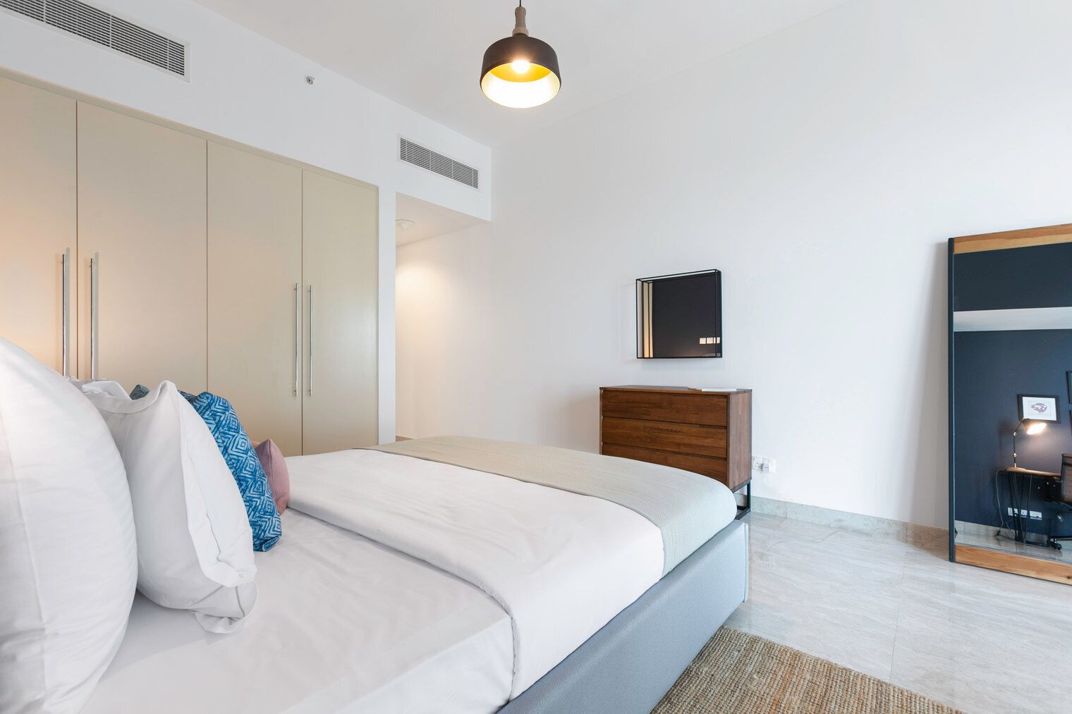 A modern bedroom with a bed, wardrobe, and a desk with a chair.