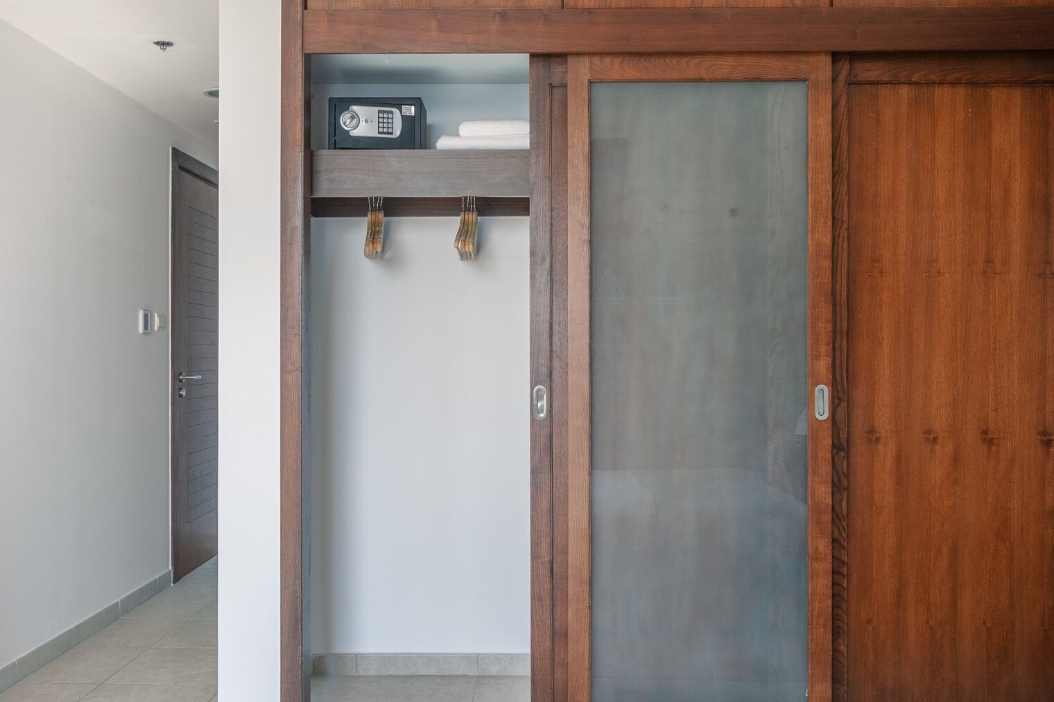 A hallway with a wooden wardrobe, a safe, and a towel rack.