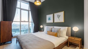 Une chambre avec un grand lit, une vue par la fenêtre et deux lampes fixées au mur.