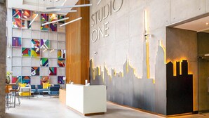 Un espace d’accueil moderne, agrémenté d’un mur au motif géométrique, d’un comptoir d’accueil et de différents espaces d’assise.