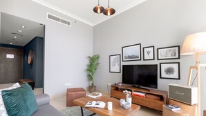 Un salon moderne avec un canapé gris, une table basse en bois, un téléviseur et des tableaux encadrés accrochés au mur.