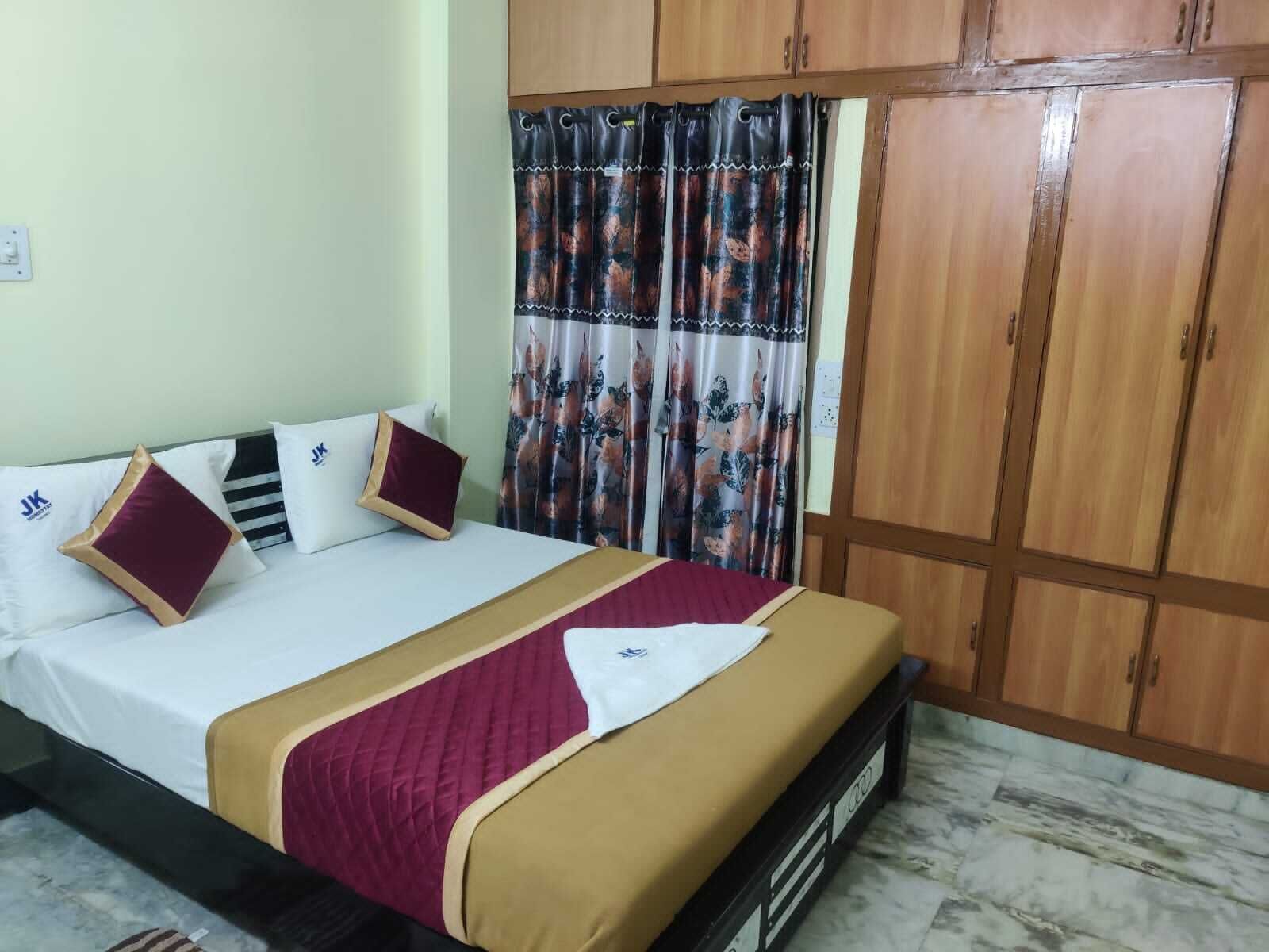 A hotel room with a bed, a wardrobe, and a window with curtains.