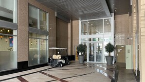 Eine moderne Hotelhalle mit Golfwagen, großen Fenstern und Zimmerpflanzen.