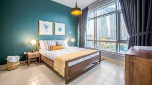 Ein modernes Schlafzimmer mit großem Fenster, einem Bett, Nachttischlampen und Bildern an der Wand.