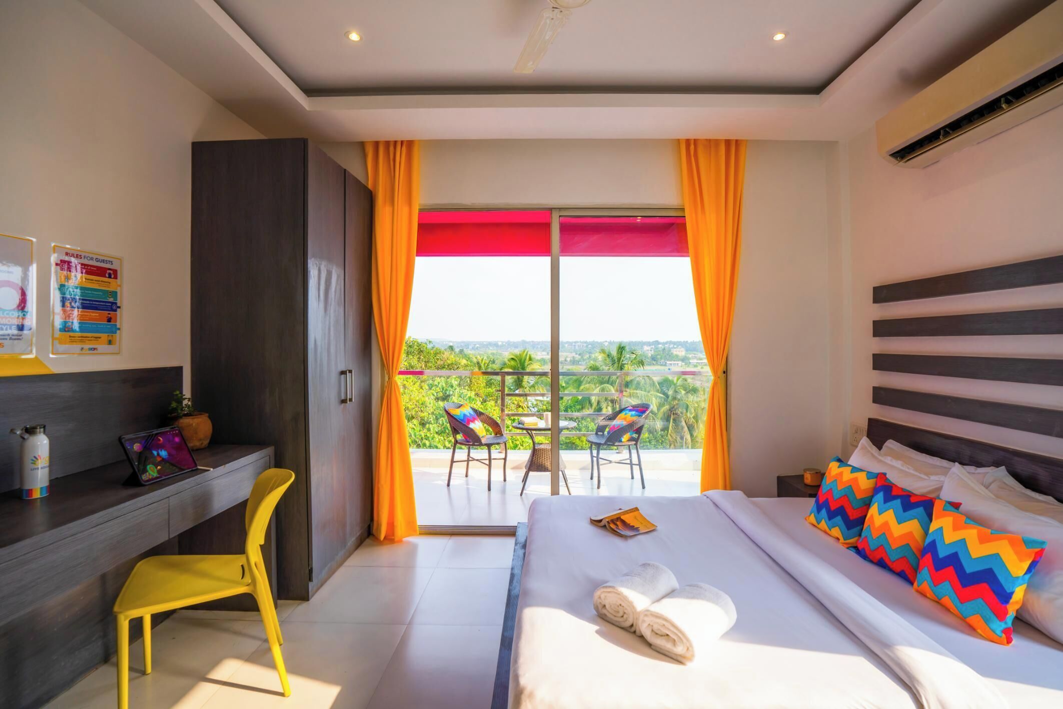 Habitación de hotel con cama, escritorio, silla y balcón con vistas.