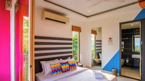 Une chambre d’hôtel avec un lit, une fenêtre, un appareil de climatisation et une salle de bain visible à travers une porte ouverte.