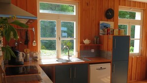 Cocina compacta con armarios de madera, un lavamanos y un refrigerador.