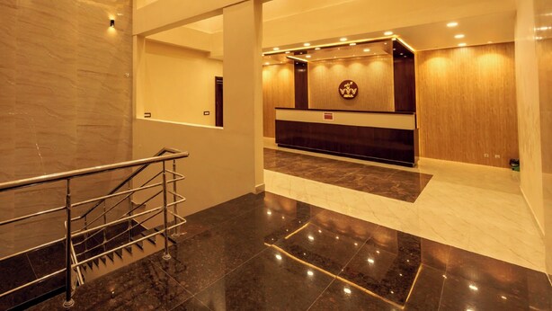 A modern hotel lobby with a reception desk, a staircase, and a marble floor. - Grand Sri Krishna Residency (Viluppuram)