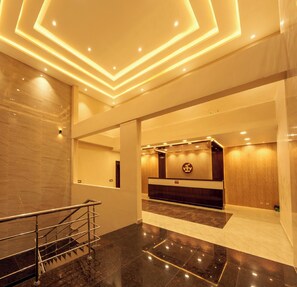 En moderne lobby med reception, trappe og marmorgulv.