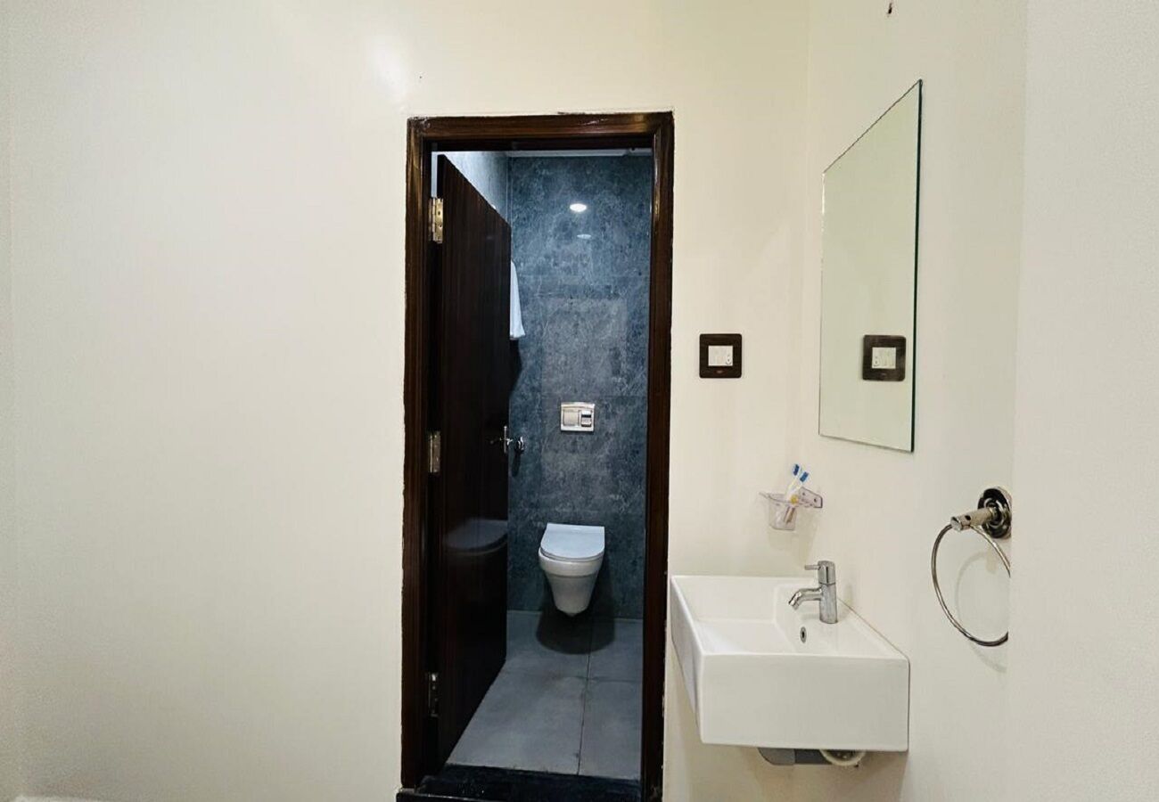 A bathroom with a toilet, sink, and mirror.