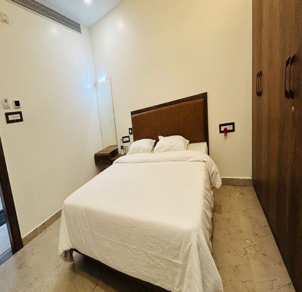 Une chambre d’hôtel avec un grand lit, une table de chevet, un miroir et une armoire.