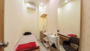 A small, clean room with a bed, a mirror, a chair, and a desk. - Grand Sri Krishna Residency (Viluppuram)