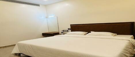 A bedroom with a bed, a nightstand, a ceiling fan, and a wall-mounted light fixture.