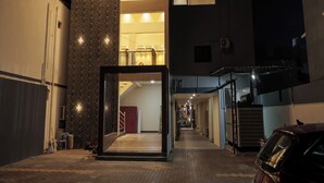 A modern building with a central staircase, a large open entrance, and a car parked outside. - Grand Sri Krishna Residency (Viluppuram)