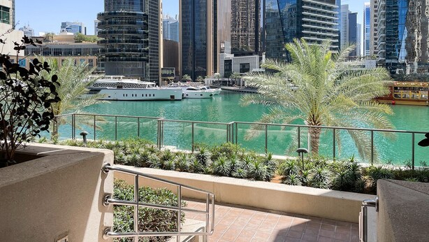 A view of a marina with boats, a water body, and modern high-rise buildings in the background. - Blueground | Dubai Marina, shared pool, nr Beach (Dubai)
