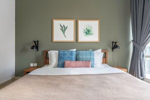 Ett snyggt och välordnat sovrum med en säng, två vägglampor och två inramade botaniska illustrationer ovanför sängen.