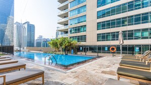 A rooftop pool with lounge chairs, a lifebuoy, and a view of high-rise buildings. - Blueground | Dubai Marina, shared pool, nr Beach (Dubai)