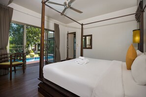 A spacious bedroom with a large bed, a ceiling fan, a view of a swimming pool, and a wooden chair. - Live the Tropical Dream at Villa Mylico (Rawai)