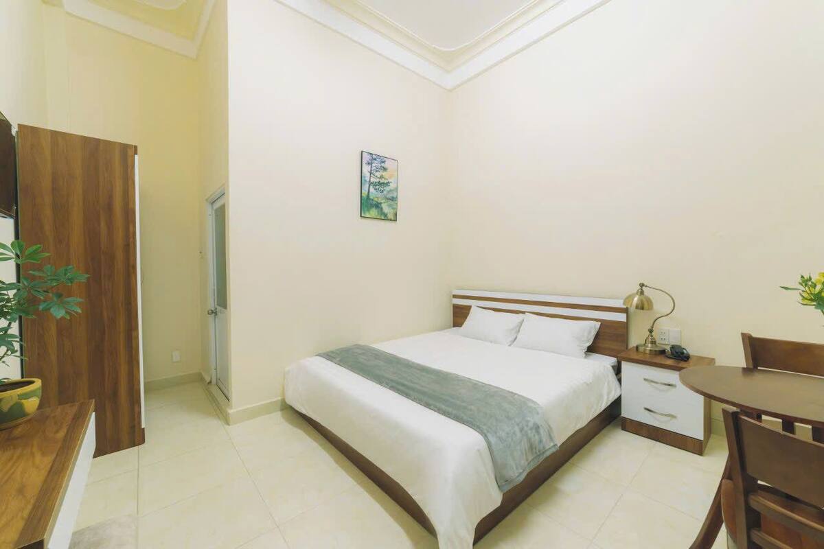 Une chambre à coucher comprenant un lit, une table de chevet, une lampe et une petite table avec des chaises.