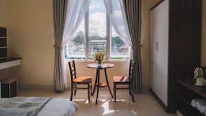 A hotel room with a bed, a desk with a chair, a wardrobe, and a window with curtains. - Phat Loi Hotel Dalat  (Xuan Huong - Da Lat)