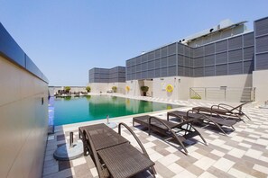A swimming pool with lounge chairs and a modern building in the background.