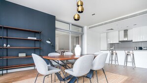A modern kitchen with white cabinets, a wooden dining table, and grey chairs. - Blueground | City Walk, pool, nr City Park (Dubai)
