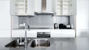 A modern kitchen with stainless steel appliances, a double sink, and open shelving. - Blueground | City Walk, pool, nr City Park (Dubai)
