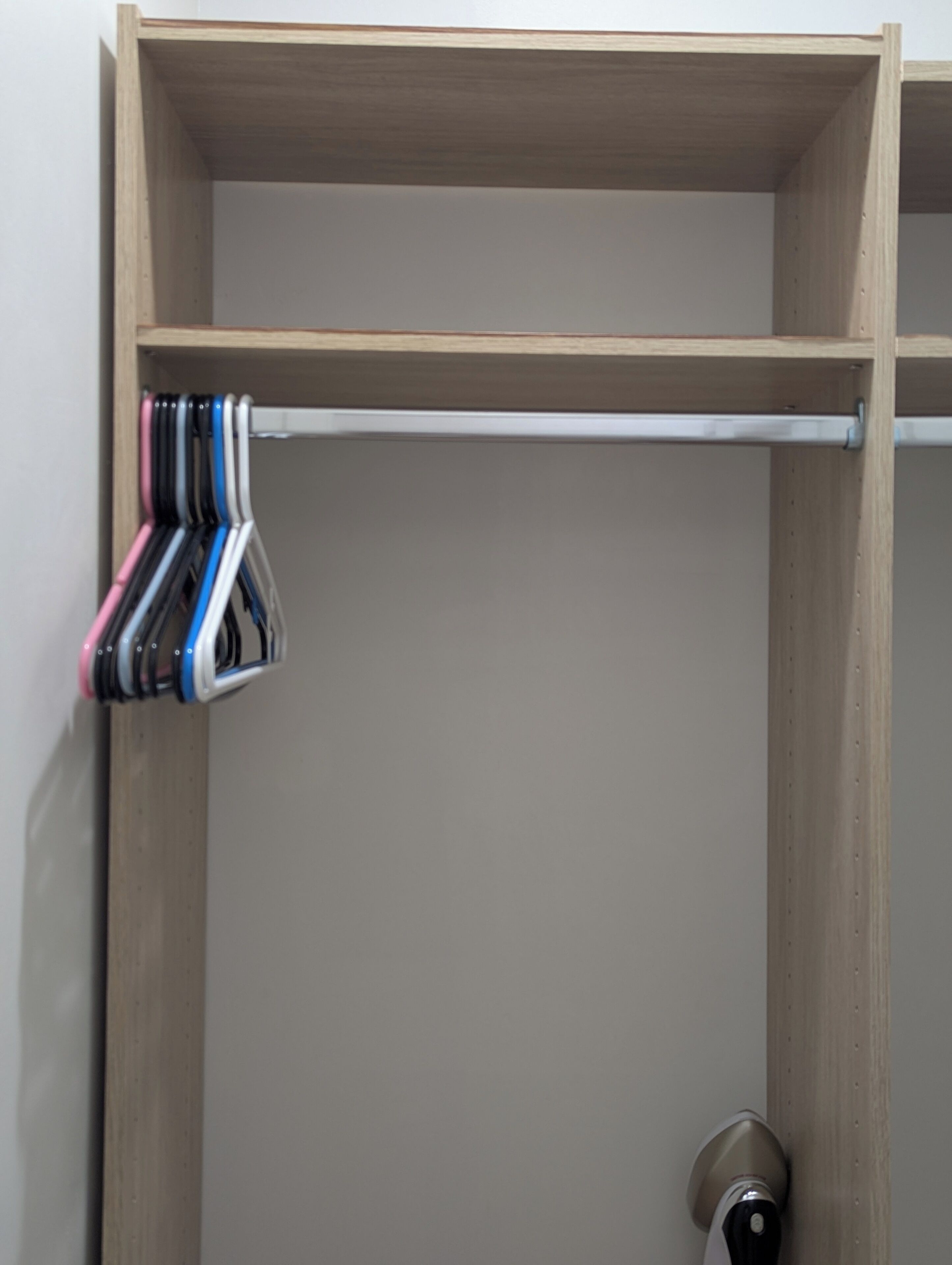 A wooden closet with a metal rod for hanging items.