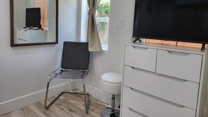 Une salle de bain avec un miroir, une chaise, un téléviseur et un meuble.
