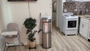 Une cuisine moderne équipée d’une cuisinière, d’un four et d’un four à micro-ondes. On y trouve également un réfrigérateur, un évier et un plan de travail avec une machine à café. Un téléviseur est fixé au mur, au-dessus de la cuisine.