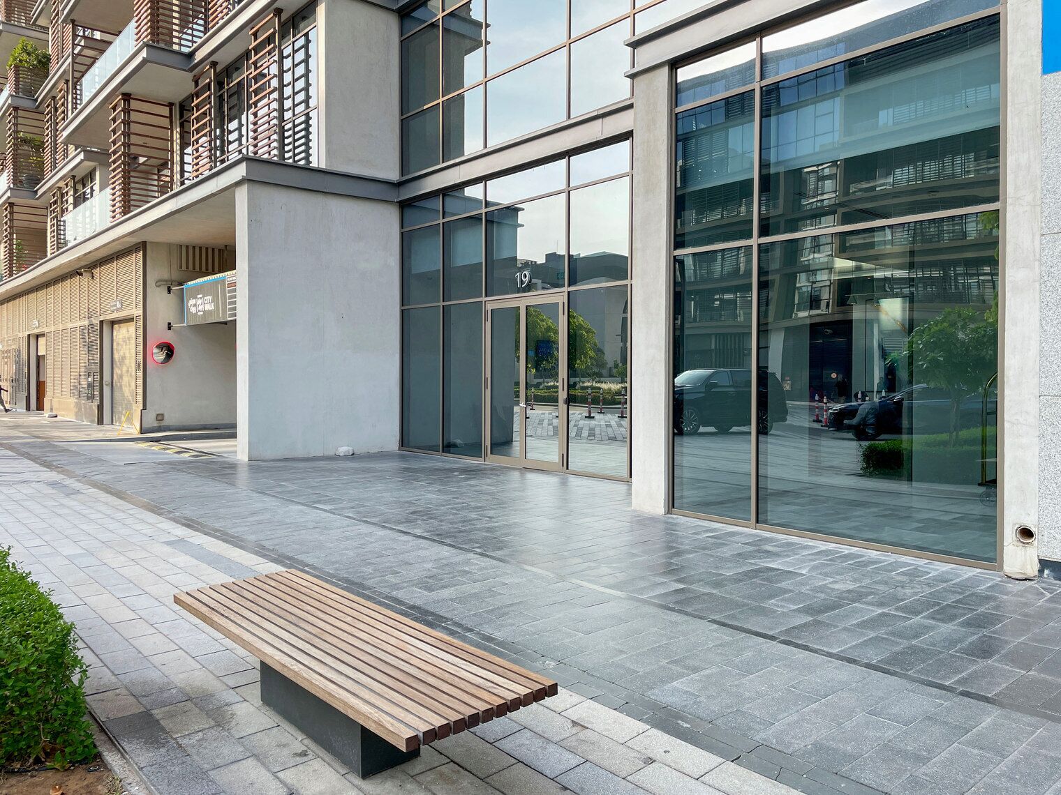 A modern building with large glass windows, a bench, and a paved walkway.