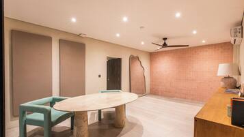 Una habitación moderna con una mesa redonda, dos sillas, un ventilador de techo y una pared con azulejos.