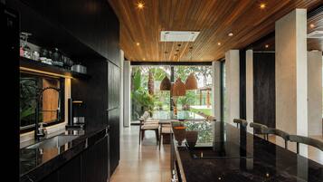 Un intérieur moderne avec un plafond en bois, un espace bar et un coin salon offrant une vue sur la verdure environnante.