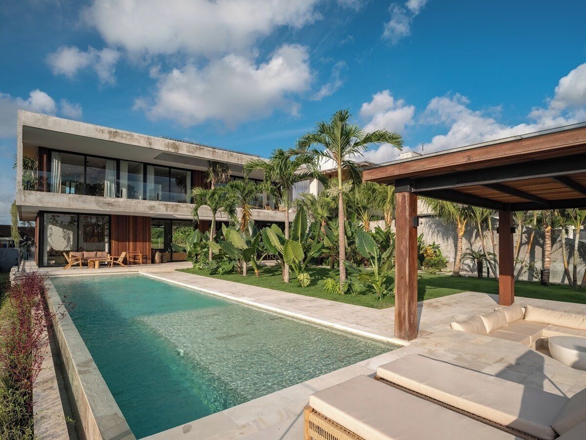 Un edificio moderno con piscina, mobiliario exterior y plantas tropicales.
