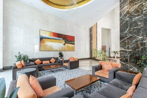 A spacious lobby with a large abstract painting, a marble reception desk, and a modern seating area with sofas and a coffee table.