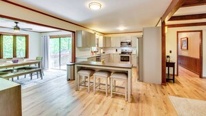 A spacious kitchen with wooden flooring, a dining area with a table and chairs, and a view of the outdoors through large windows. - Deck & Game Room: Mountaintop Hideaway in Tiger! (Tiger)