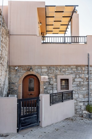 A building with a stone facade, a wooden door, a balcony with a metal railing, and a sign that reads 'Casa Bettina.' - Casa Betini | Charming Traditional Maisonette with Jacuzzi & Stunning Bay Views (Schisma Eloundas)