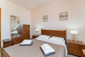 A hotel room with a bed, two bedside tables, a wardrobe, and two wall-mounted lamps. - Casa Betini | Charming Traditional Maisonette with Jacuzzi & Stunning Bay Views (Schisma Eloundas)
