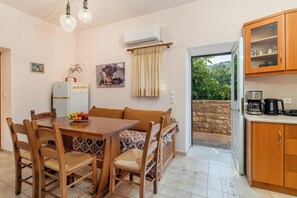 Un coin repas avec une table et des chaises en bois, un réfrigérateur et une cuisine équipée d’armoires.