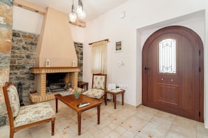 A living room with a fireplace, wooden furniture, and a large wooden door.