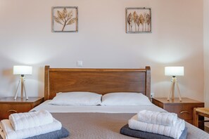 A hotel room with a wooden headboard, two bedside tables with lamps, a bed with white linens, and two wall-mounted artworks.