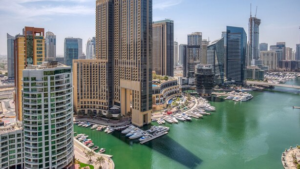Un edificio alto con un puerto deportivo y barcos.