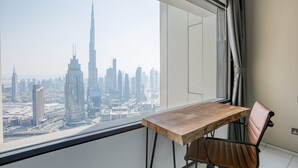 A room with a view of a city skyline, a wooden table, and a single chair.