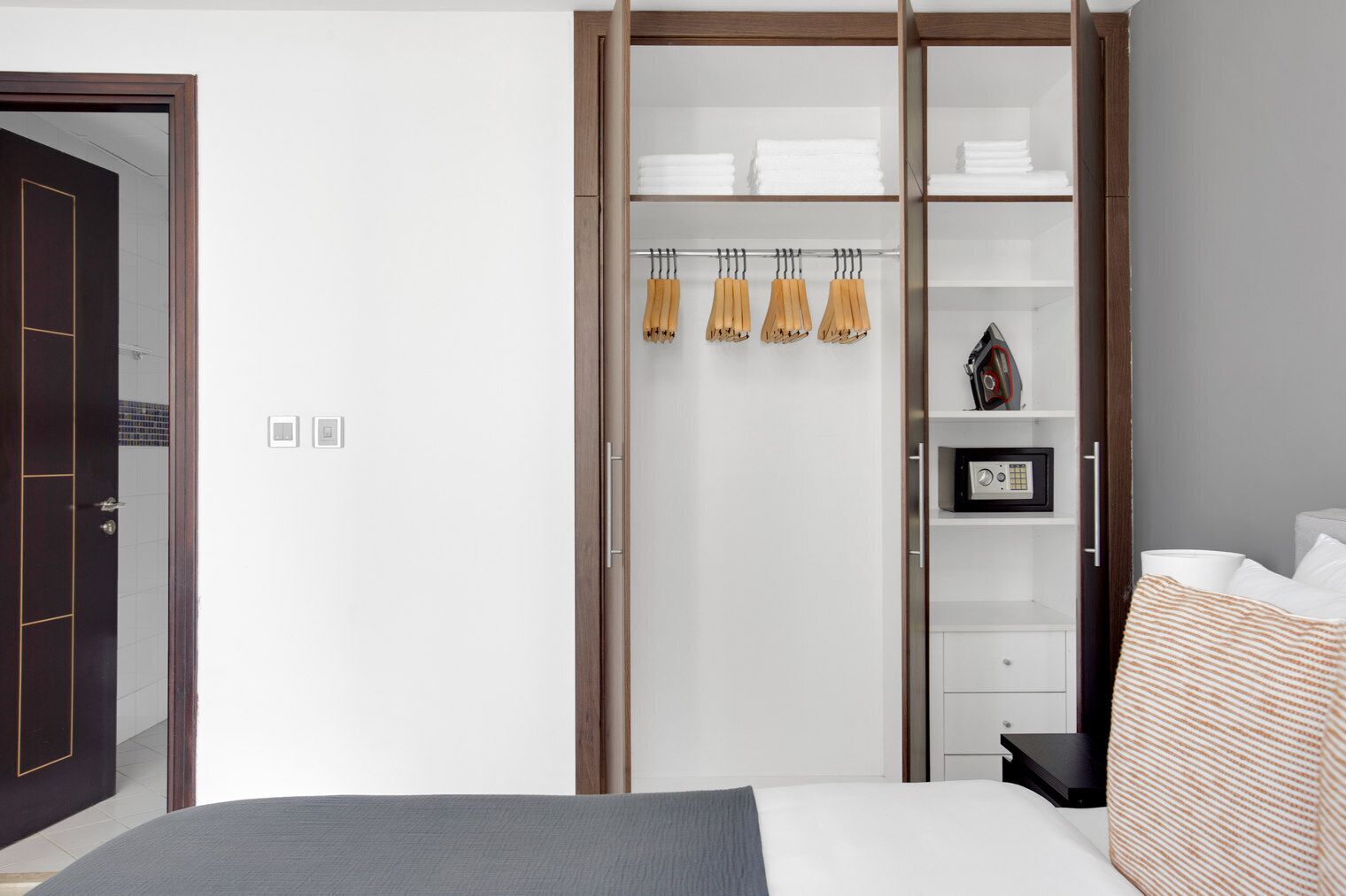 Ein Schlafzimmer mit Bett, einem Kleiderschrank mit Kleidung und einem Regal mit Toilettenartikeln.