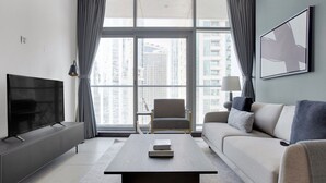 A modern living room with a flat-screen TV, a sofa, a coffee table, and a chair. - Blueground | JLT, pool, nr Marina (Dubai)